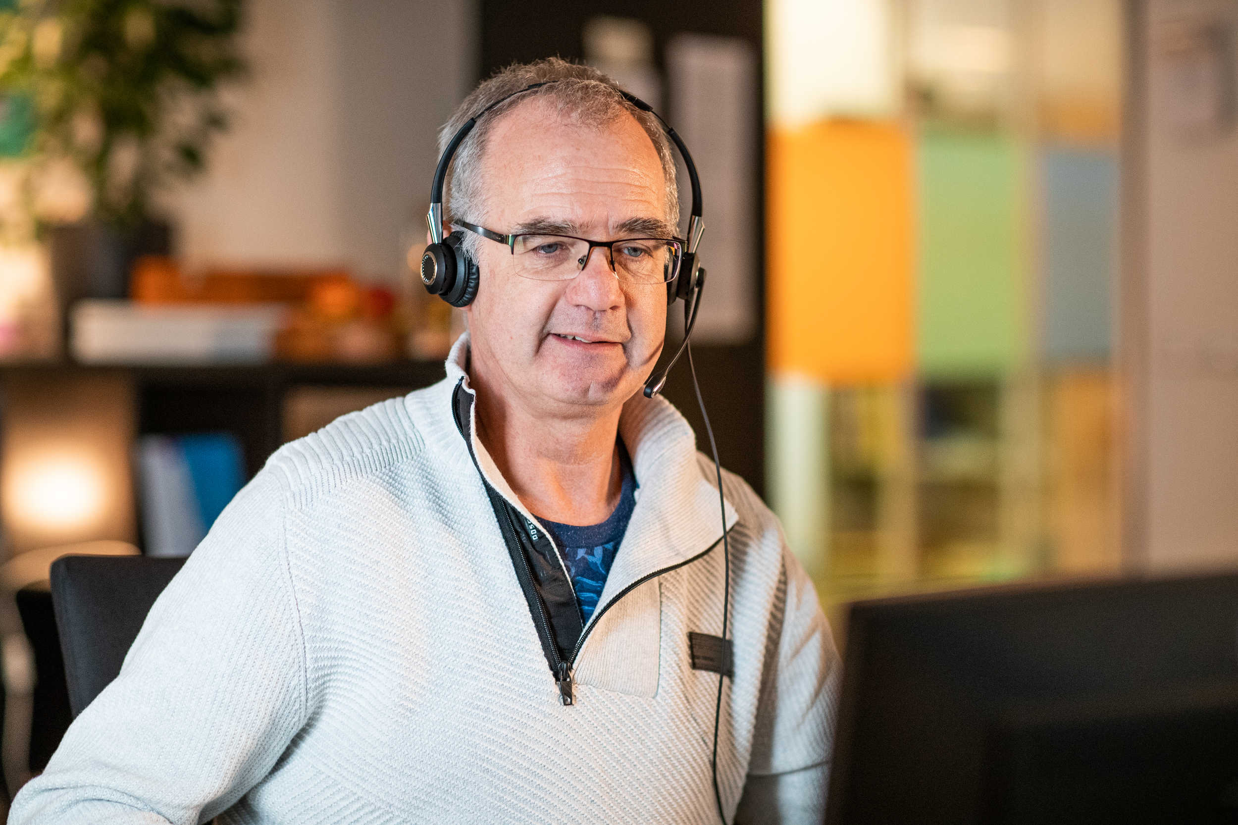 Kindertelefoon vrijwilliger luistert via headset achter computer